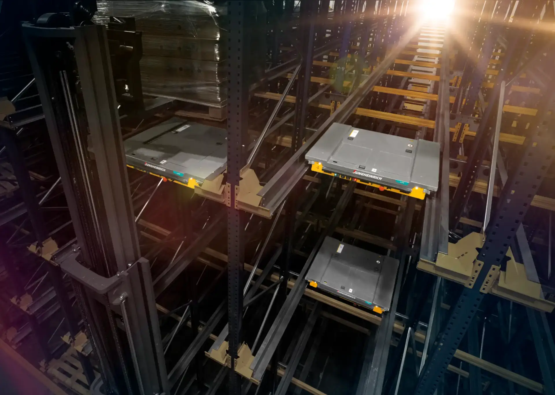 מבט על זוג שאטלים אוטונומיים יושבים על מסילות בתוך מדפים קומפקטיים גבוהים, כשמשטח פלטה מונח על הרכיב